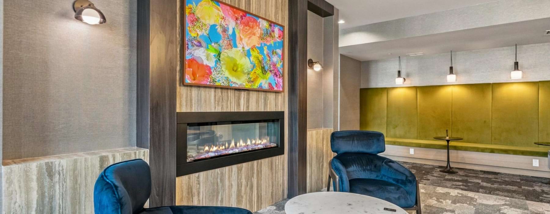 Seating area with blue chairs by fireplace and green bench across