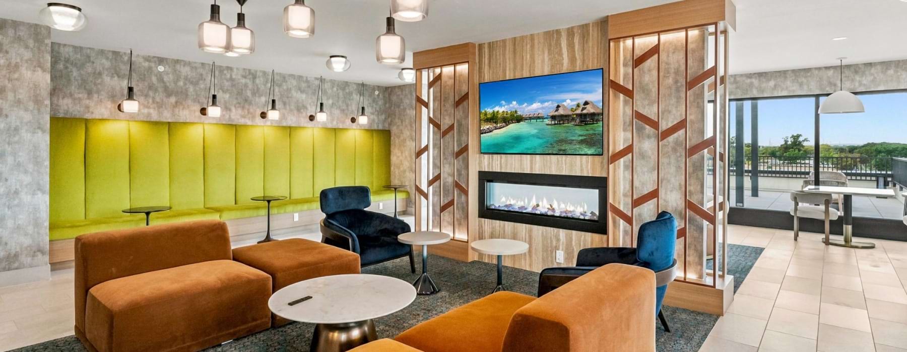 Clubroom with green, orange, and blue seating areas by fireplace 